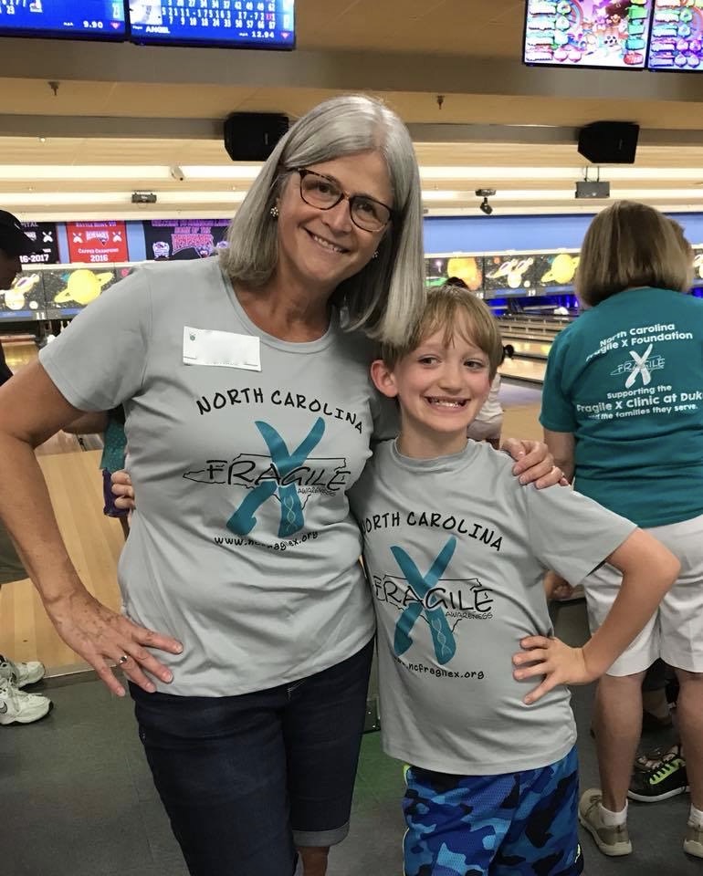 Woman with arm around younger person having fun at a bowling alley.