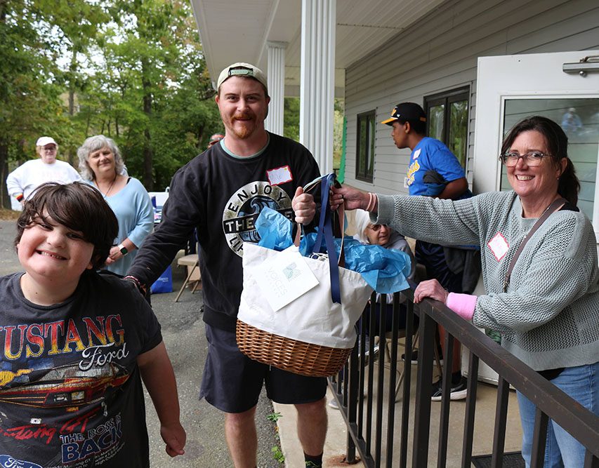 Ashley Keith of Voices Together hands the gift basket to raffle winner Mike Strickland pictured with his son Avi.