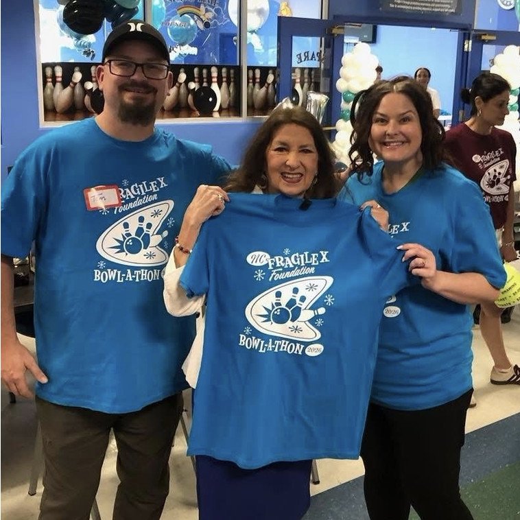 Representative Donna White (center) accepts a 2026 Bowl-a-Thon T-shirt from Tom Miller and NCFXF President Brittney Miller.
